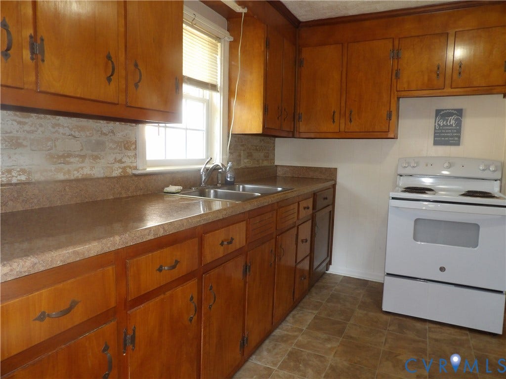 3206 South Street, Chester, VA 23831 Kitchen featuring wood cabinetry, integrated countertops with a double-basin sink, exposed brick-style backsplash, and a white freestanding electric range