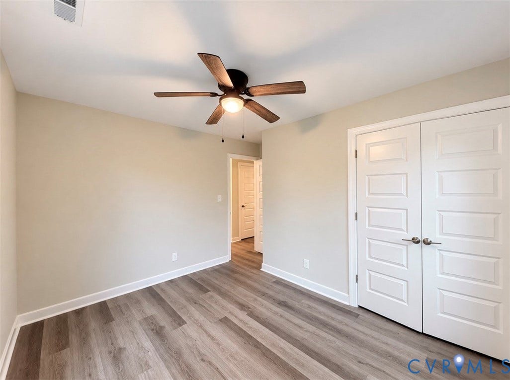 2800 Harris Hill Road, Dunnsville, VA 22454 Wood-finish flooring, neutral wall tones, multi-paneled double closet doors with satin nickel hardware, and a center-mounted ceiling fan with integrated lighting