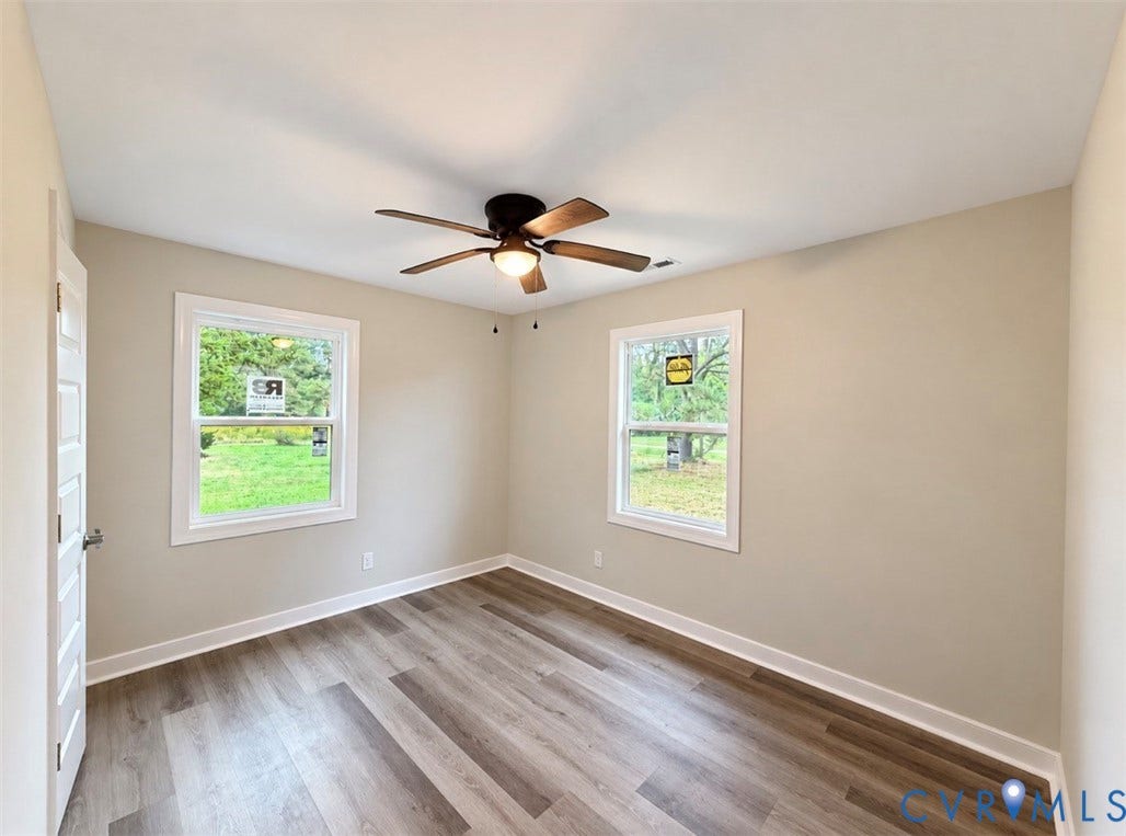 2800 Harris Hill Road, Dunnsville, VA 22454 Neutral-toned room featuring wood-finish flooring, a ceiling fan with integrated lighting, and dual windows with white casing