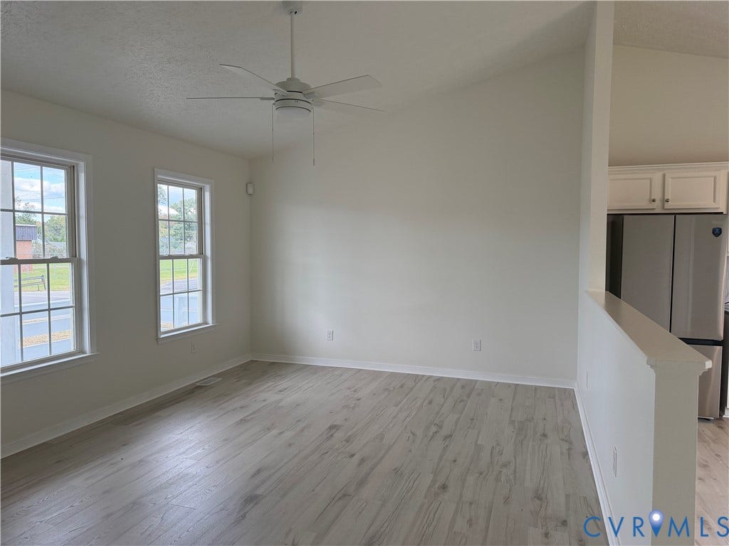 Vaulted ceilings, wood-finish flooring, white cabinetry, dual-pane windows, and a ceiling fan