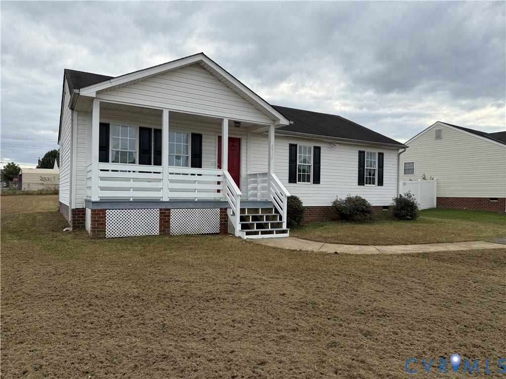 Vinyl siding exterior featuring a covered front porch, brick foundation accent, shutter-clad windows, and a paved walkway