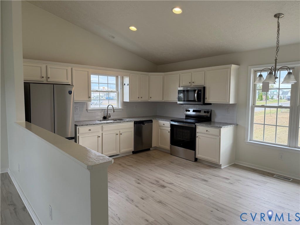 Kitchen featuring white cabinetry, stone-finish countertops, stainless steel appliances, wood-finish flooring, and vaulted ceilings