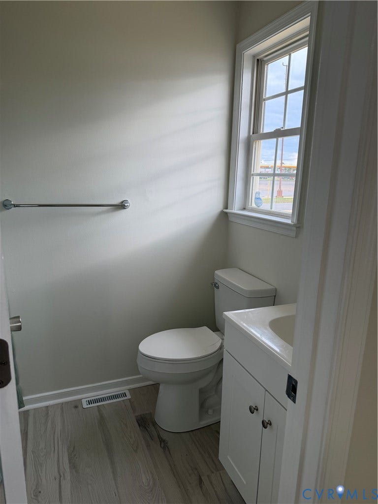 Wood-finish flooring, white cabinetry with integrated sink, chrome hardware, and single-hung window with muntins