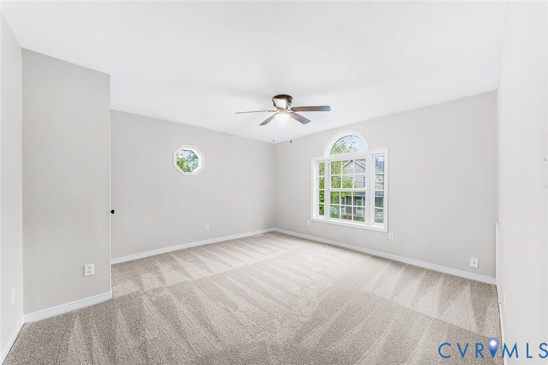 1802 Maury Street, Richmond, VA 23224 Neutral-toned interior featuring wall-to-wall carpeting, an arched window, a secondary octagonal window, and a central ceiling fan