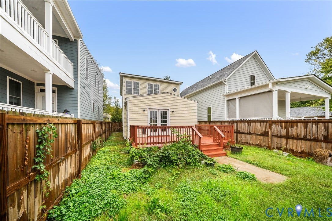 1802 Maury Street, Richmond, VA 23224 Exterior rear elevation featuring lap siding, double glass-pane doors, an elevated wood deck with railing, and a fenced perimeter