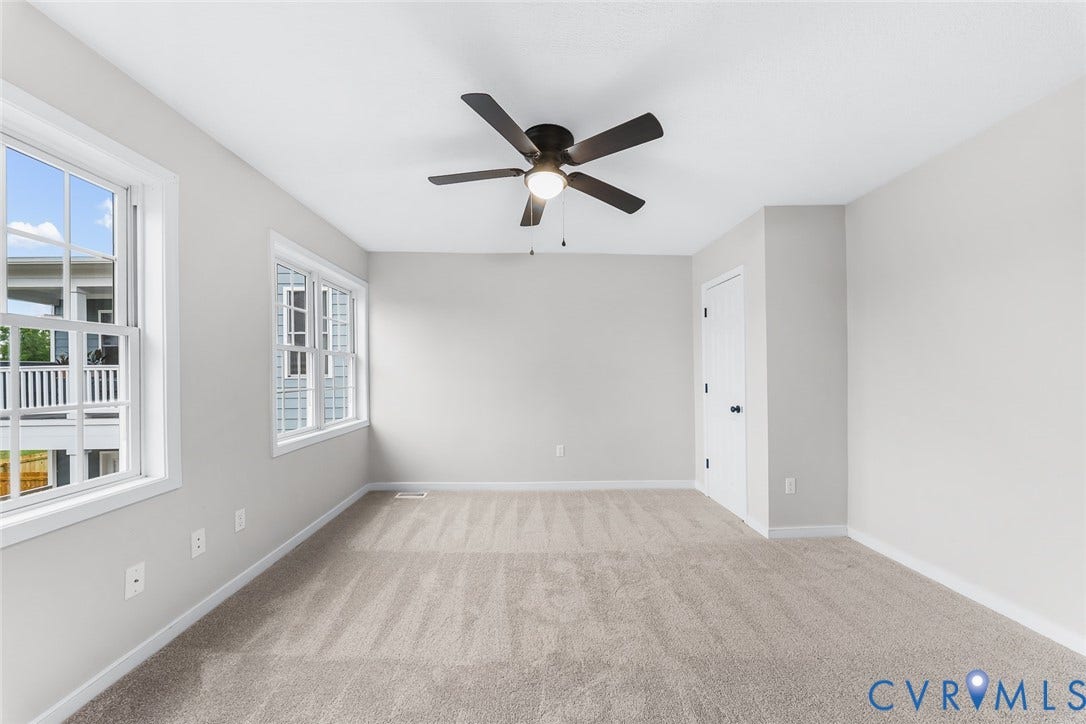 1802 Maury Street, Richmond, VA 23224 Neutral-toned interior featuring wall-to-wall carpeting, multiple double-hung windows, and a ceiling fan with integrated lighting