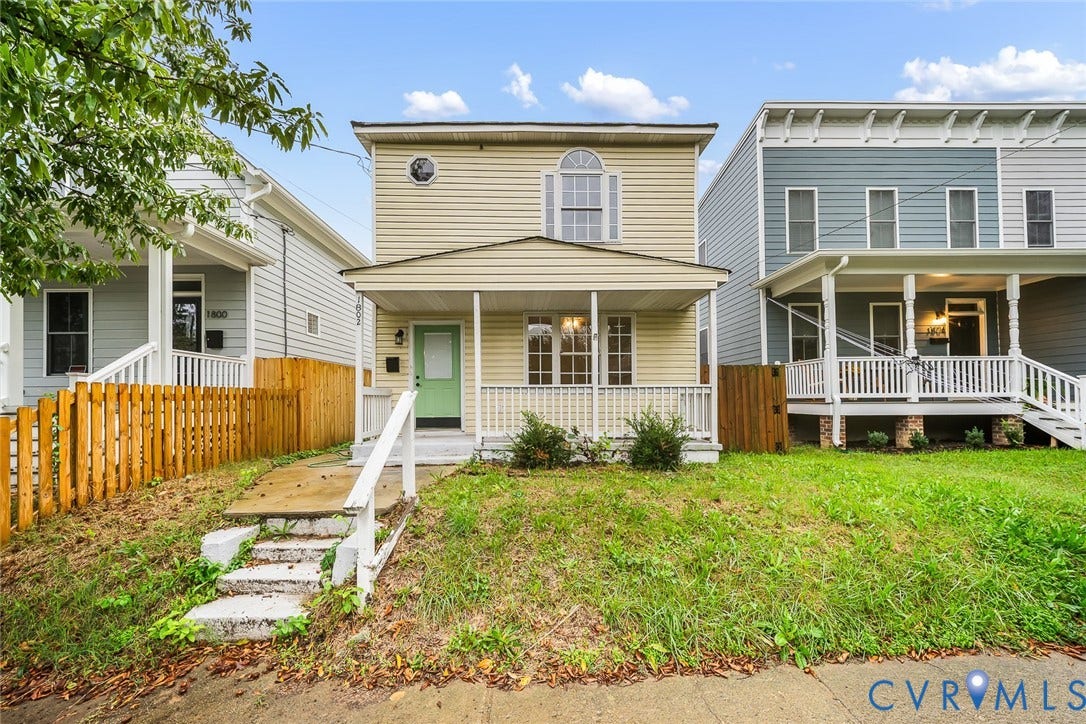 1802 Maury Street, Richmond, VA 23224 Two-story residence featuring light-colored horizontal siding, a covered front porch with white railing, arched window detailing, and a fenced front yard