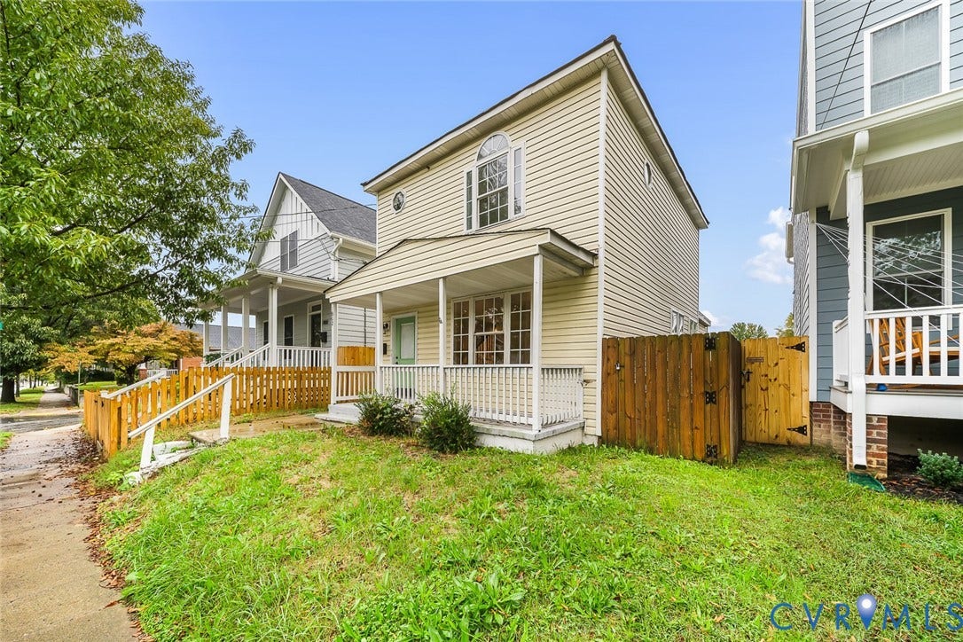 1802 Maury Street, Richmond, VA 23224 Vinyl-sided exterior featuring a covered front porch with white railing, arched window detailing, and a privacy wood fence
