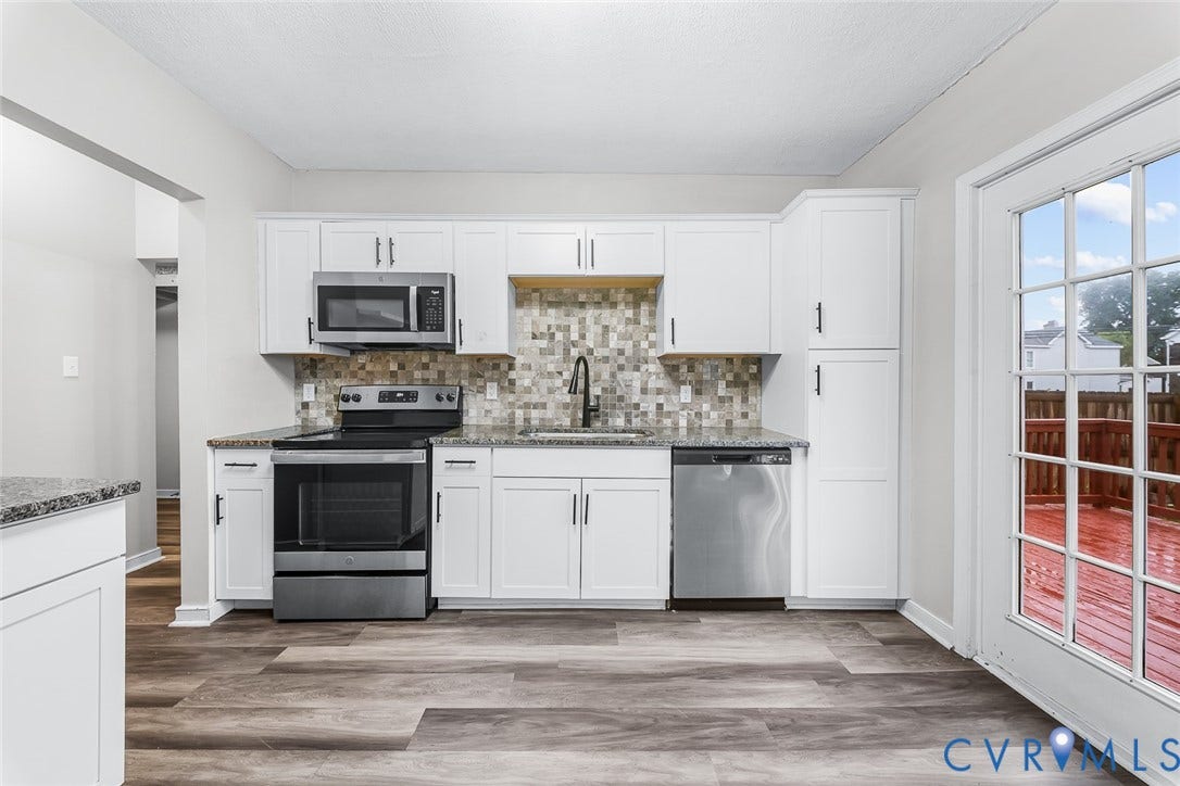 1802 Maury Street, Richmond, VA 23224 Kitchen featuring white Shaker-style cabinetry, stone-finish countertops, mosaic tile backsplash, stainless steel appliances, and wood-finish flooring