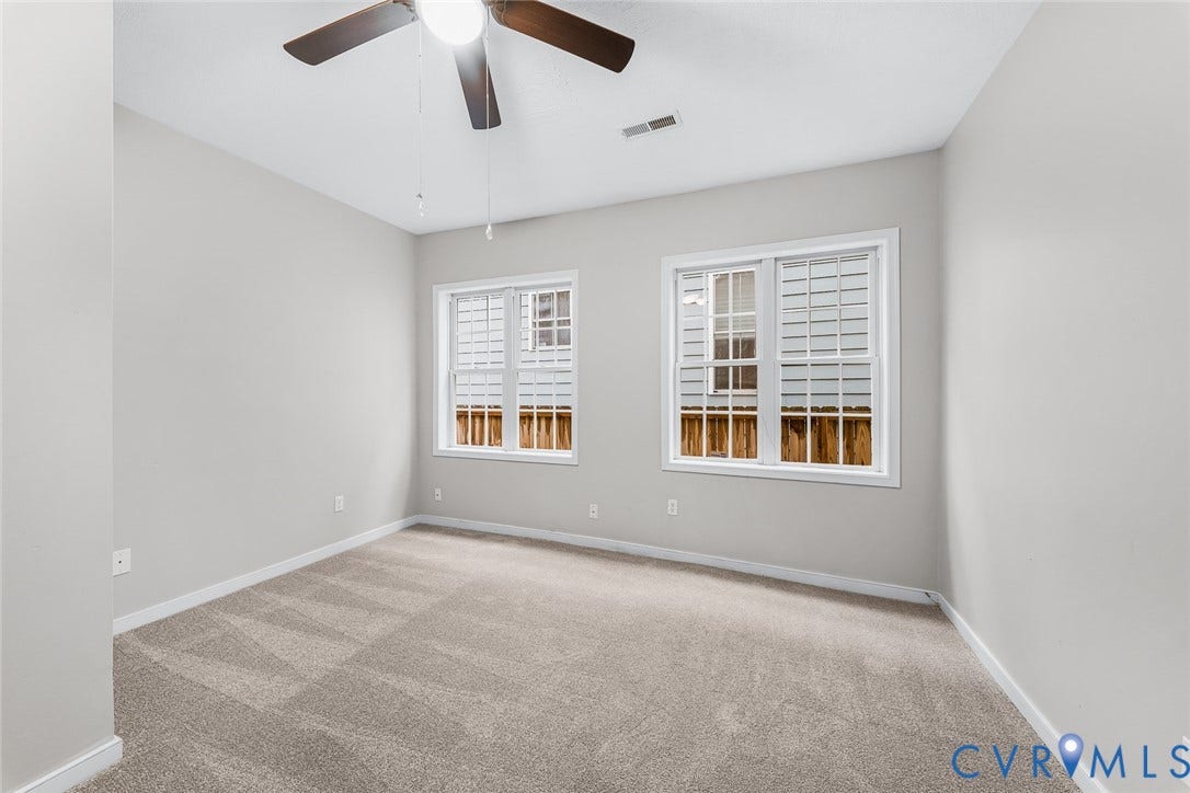 1802 Maury Street, Richmond, VA 23224 Neutral wall tones, wall-to-wall carpeting, two multi-pane windows with white trim, and a ceiling-mounted light fixture with fan blades