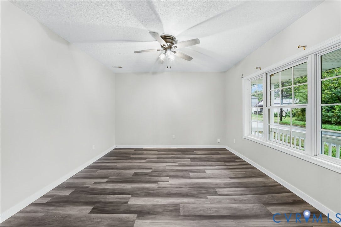 1802 Maury Street, Richmond, VA 23224 Neutral-toned interior space featuring wood-finish flooring, vaulted ceilings, a ceiling fan with integrated lighting, and expansive windows