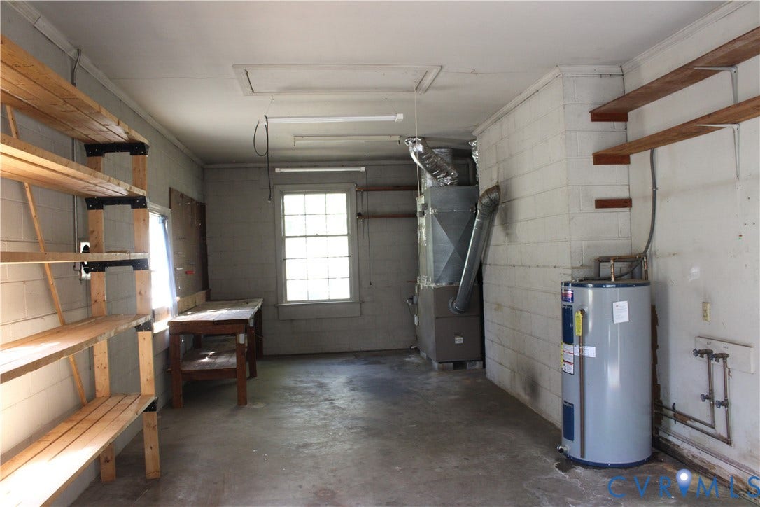 4101 Vauxhall, Chesterfield, VA 23234 Utility space featuring exposed masonry walls, wooden wall-mounted shelving units, concrete flooring, a multi-pane window, and integrated heating and plumbing systems