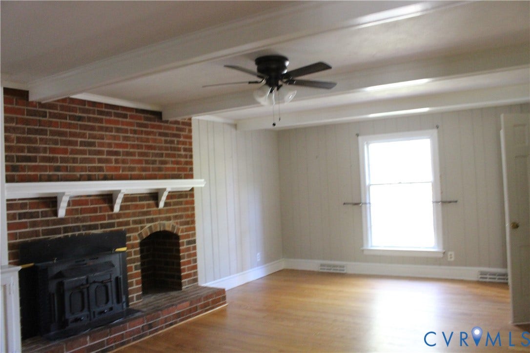 4101 Vauxhall, Chesterfield, VA 23234 Exposed ceiling beams, brick fireplace featuring a wood-burning insert and mantel, wood-finish flooring, and a ceiling fan with integrated lighting