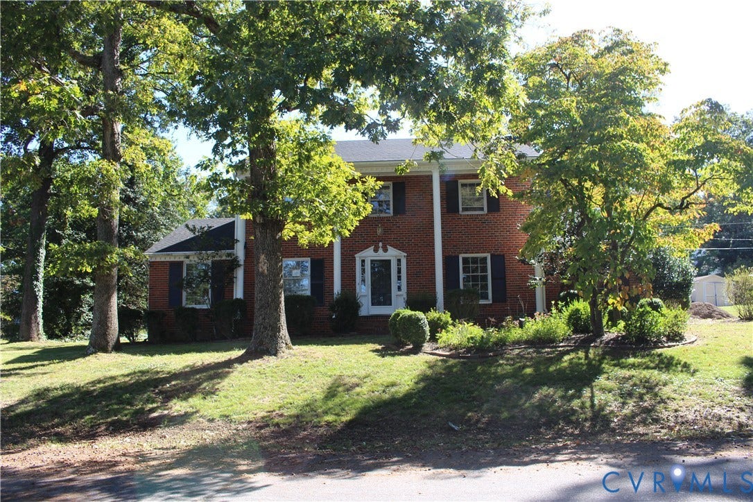 4101 Vauxhall, Chesterfield, VA 23234 Two-story brick exterior featuring classic white columns, a covered entryway, decorative dark shutters, and a mature tree-lined landscape