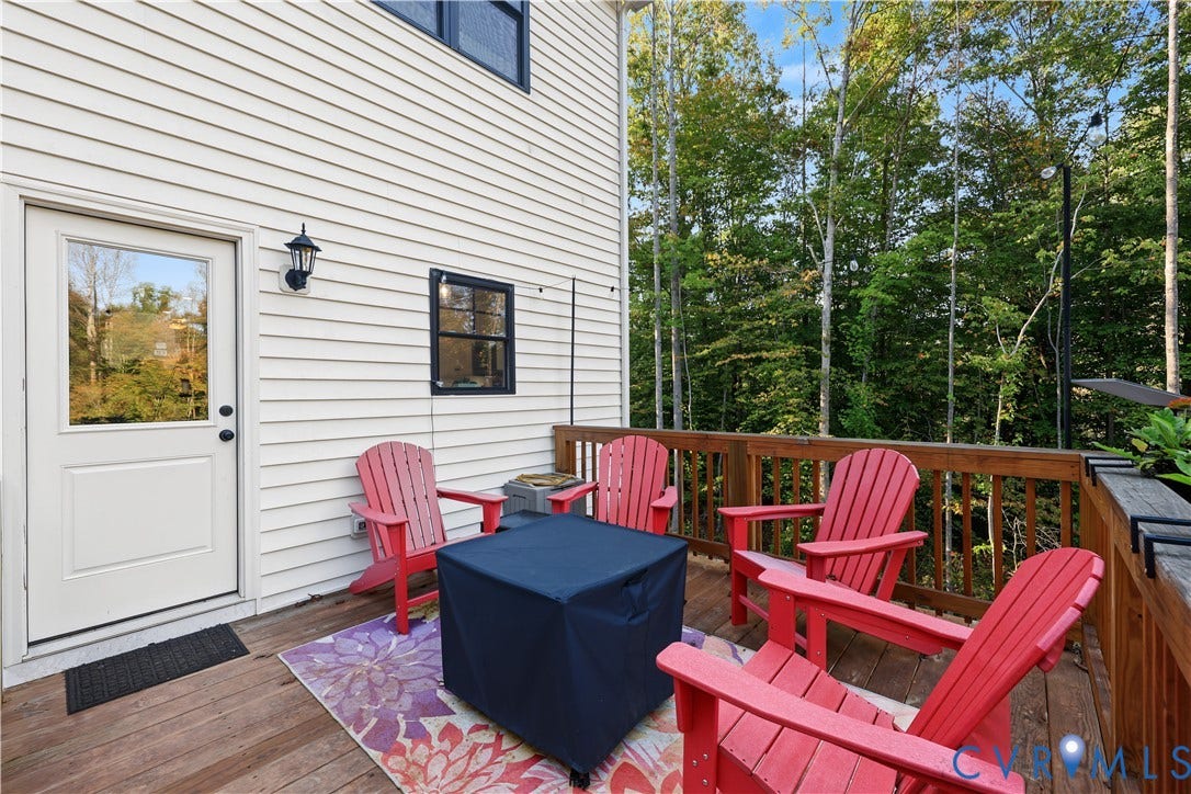 3851 County Line Road, Flemings Mill, Goochland, VA 23084 Exterior wood deck featuring a railing and attached wall-mounted light fixture, with light-colored horizontal siding and a glass-paneled door