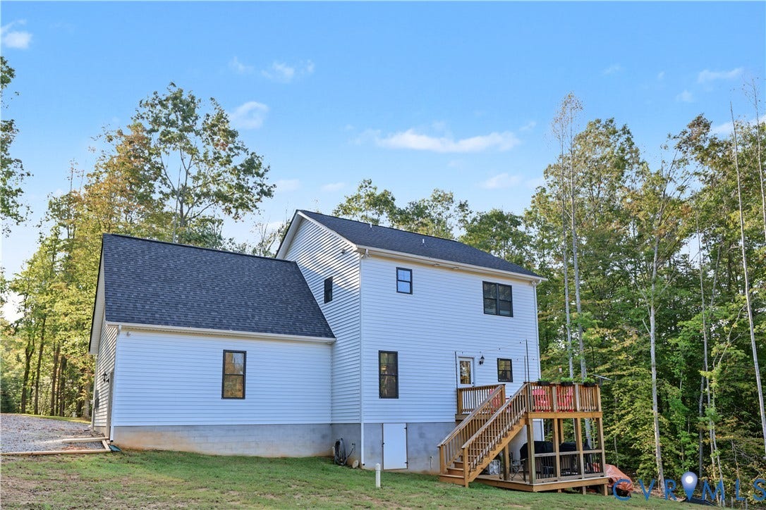 3851 County Line Road, Flemings Mill, Goochland, VA 23084 Two-story home with white horizontal siding, asphalt shingle roofing, elevated wood deck with stairs, and exterior basement access door