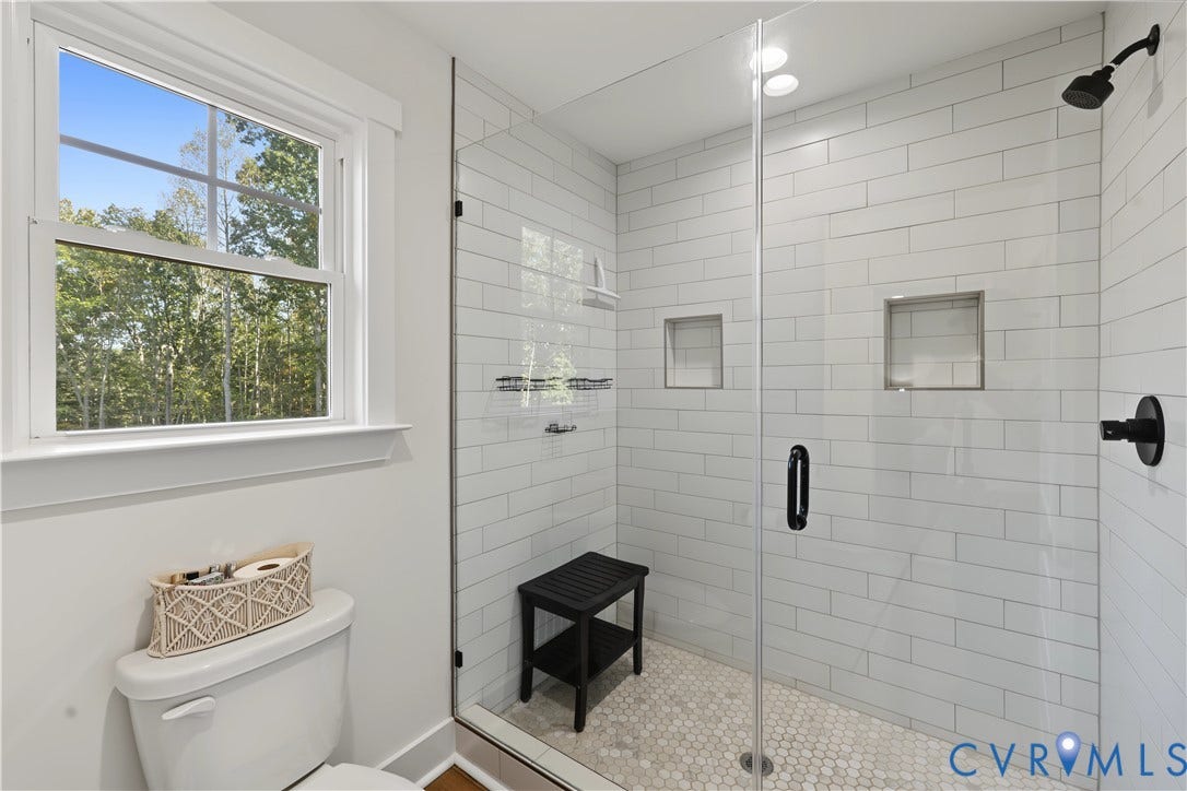 3851 County Line Road, Flemings Mill, Goochland, VA 23084 Walk-in shower featuring white subway tile walls, a frameless glass door, dual built-in wall niches, and a penny-round tile floor