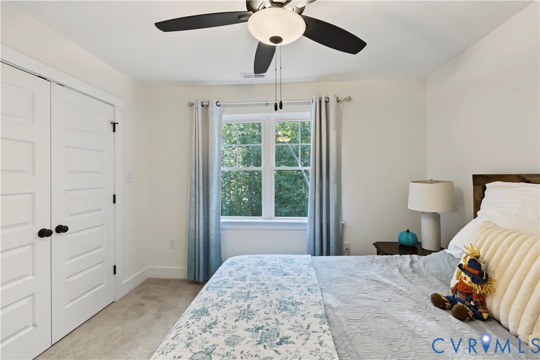 3851 County Line Road, Flemings Mill, Goochland, VA 23084 Double-door closet with panel detailing, ceiling fan with integrated lighting, window with multi-pane grilles, and neutral-toned wall-to-wall carpeting