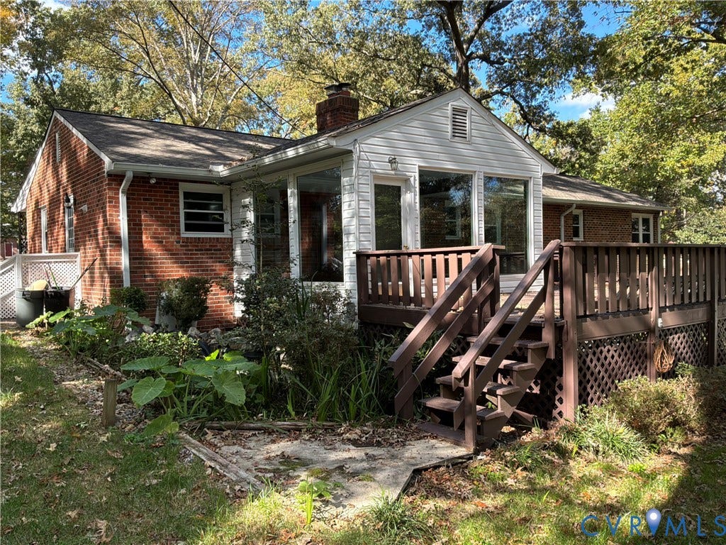 7090 Sunnyside Drive, Mechanicsville, VA 23111 Exterior featuring red brick masonry, white wood siding, a brick chimney, and a multi-level wood deck with lattice skirting