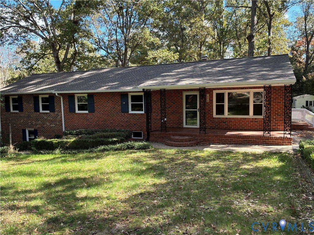 7090 Sunnyside Drive, Mechanicsville, VA 23111 Traditional brick exterior featuring decorative wrought iron porch supports, covered brick front porch, and mature surrounding landscape