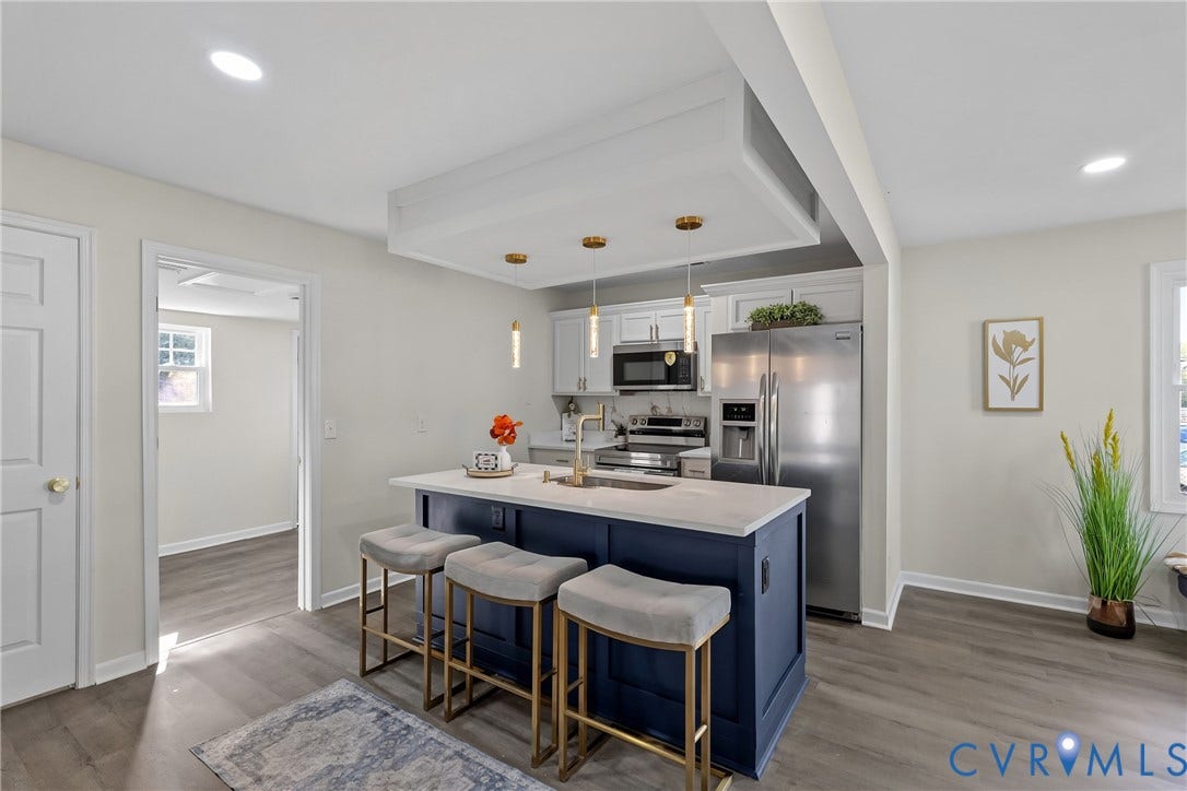 3207 Winchester Street, Henrico, VA 23231 Kitchen featuring a central island with a solid surface countertop, contrasting navy blue cabinetry, stainless steel appliances, recessed ceiling lighting, and wood-finish flooring