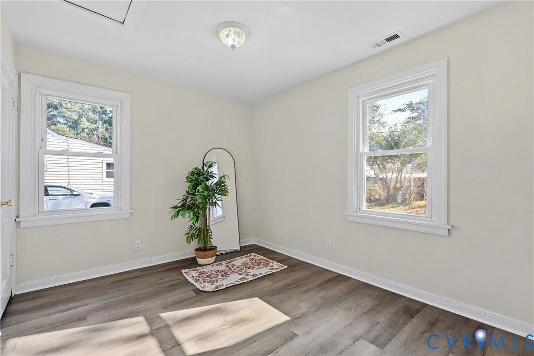 3207 Winchester Street, Henrico, VA 23231 Interior space featuring neutral wall paint, wood-finish flooring, two double-hung windows with white casing, and a flush-mount ceiling light fixture