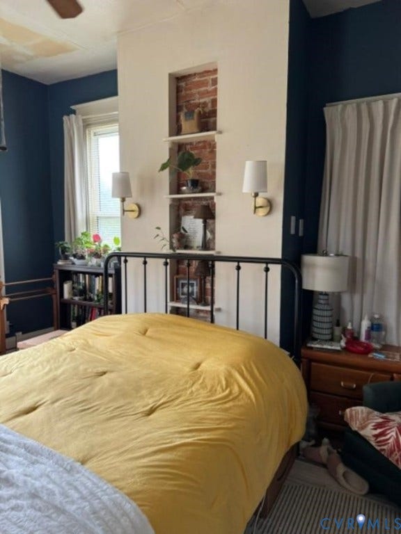 18194 S. Railroad Avenue, Boykins, VA 23827 Exposed brick accent wall with recessed built-in shelving, dual wall-mounted brass light fixtures, and multi-pane window with traditional casing