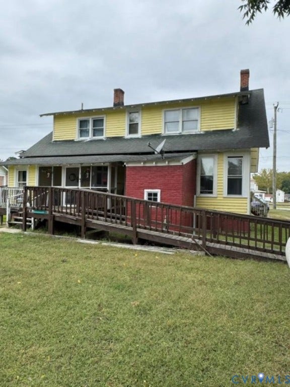 18194 S. Railroad Avenue, Boykins, VA 23827 Two-story exterior featuring yellow horizontal siding, a red brick base, two brick chimneys, and an attached wood-railing ramp