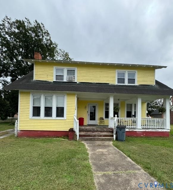 18194 S. Railroad Avenue, Boykins, VA 23827 Two-story exterior featuring yellow lap siding, a wrap-around front porch with square columns, a dark shingled roof, and a concrete walkway