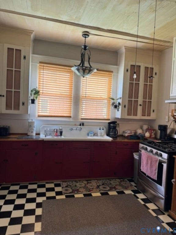 18194 S. Railroad Avenue, Boykins, VA 23827 Kitchen featuring cabinetry with paneled upper doors, high-back apron-front sink, tongue-and-groove ceiling paneling, and checkered tile flooring