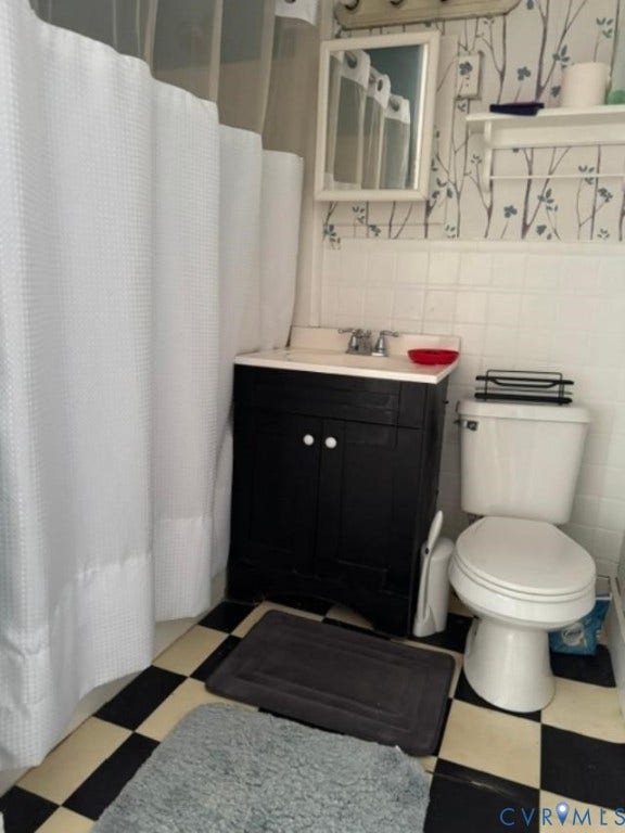 18194 S. Railroad Avenue, Boykins, VA 23827 Black vanity with a white countertop, wall-mounted rectangular mirror, built-in shelving, checkered flooring, and white square-tile wall surround