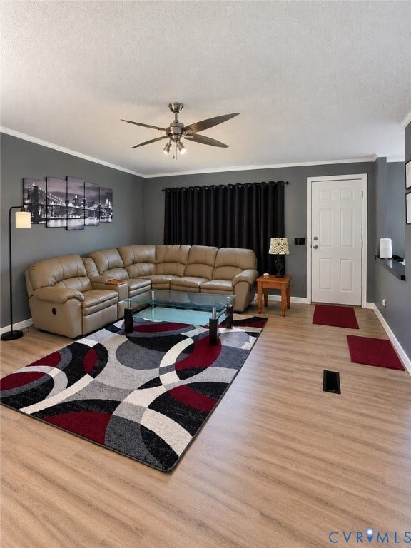 Living area featuring wood-finish flooring, a multi-blade ceiling fan with integrated lighting, and a six-panel entry door