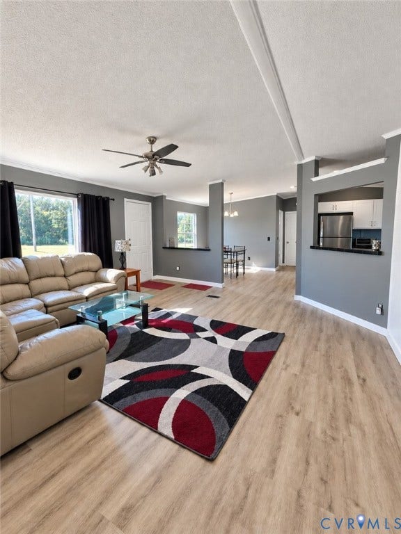 Living area featuring wood-finish flooring, neutral grey wall paint, a ceiling-mounted fan, and a pass-through opening to the kitchen