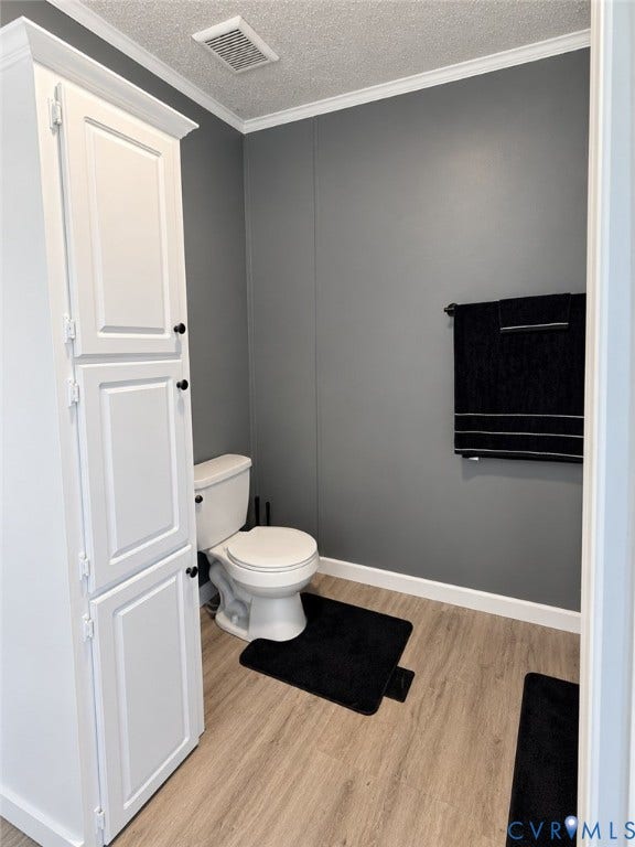 Tall white built-in cabinetry, wood-finish flooring, and white plumbing fixtures