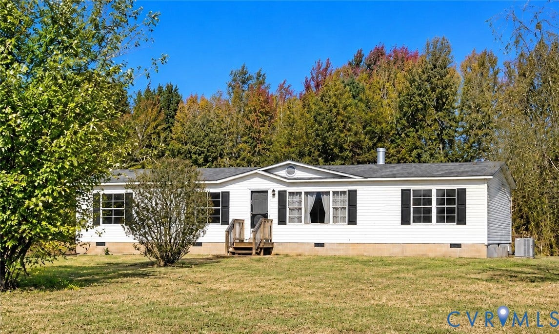 Single-story exterior featuring white horizontal siding, dark window shutters, a peaked roofline, and wood-step entry