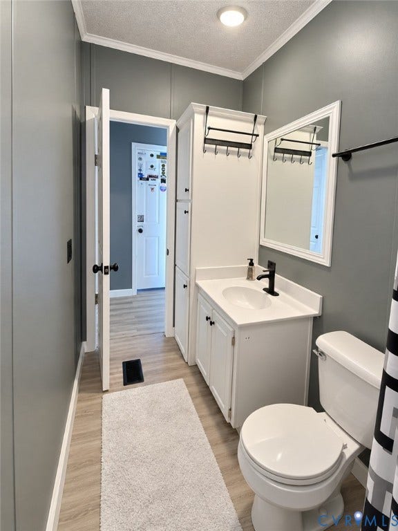 Bathroom featuring a white vanity cabinet with a quartz-style countertop, oval undermount sink, matte black hardware, integrated tall storage cabinetry, and wood-finish flooring