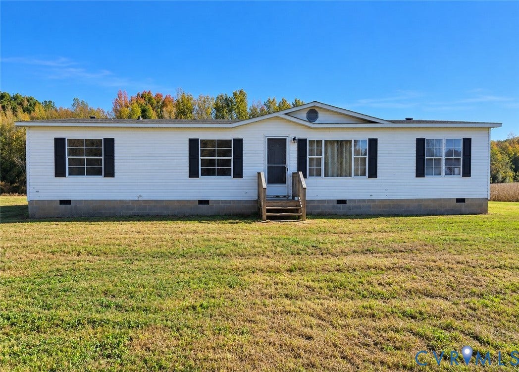 Single-level exterior featuring white siding, contrasting shutters, a gable roofline, and a concrete block foundation