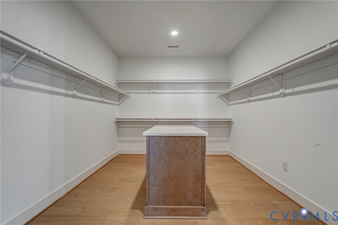 12101 Blunt's Bridge Estates Court, Blunt's Bridge Estates, Doswell, VA 23047 Walk-in storage space featuring wood-finish flooring, white shelving tiers, lighting, and a central island with a solid surface countertop