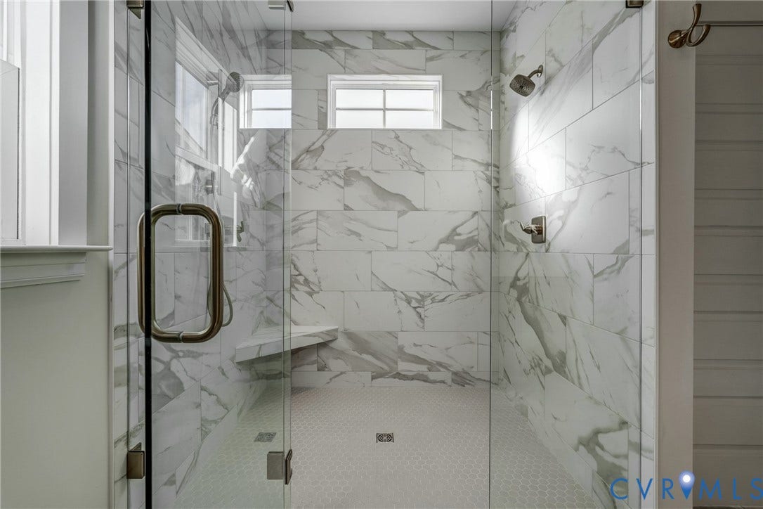 12101 Blunt's Bridge Estates Court, Blunt's Bridge Estates, Doswell, VA 23047 Walk-in shower featuring large-format stone-patterned wall tile, frameless glass enclosure, built-in corner bench, and dual wall-mounted shower heads