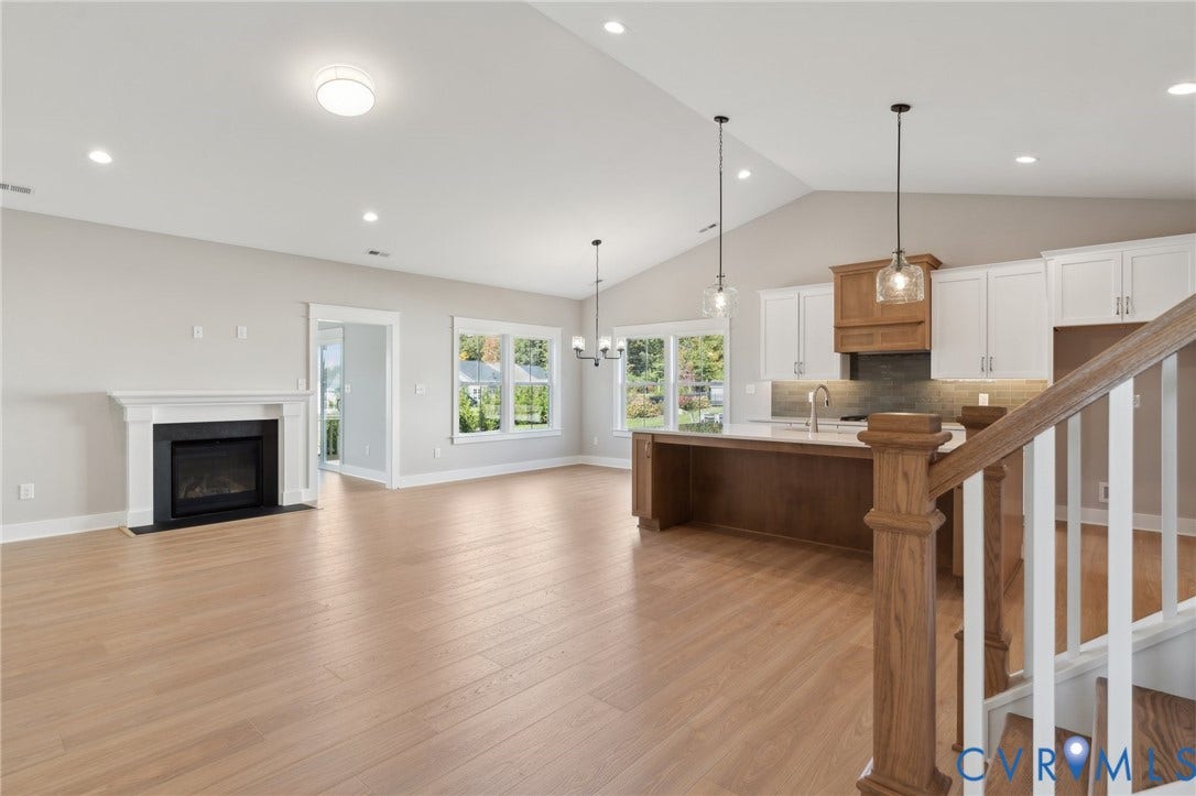 9131 Terroir Lane, Viniterra Villas, New Kent, VA 23124 Vaulted ceilings, wood-finish flooring, fireplace with a white mantel, kitchen island with wood cabinetry, and recessed lighting