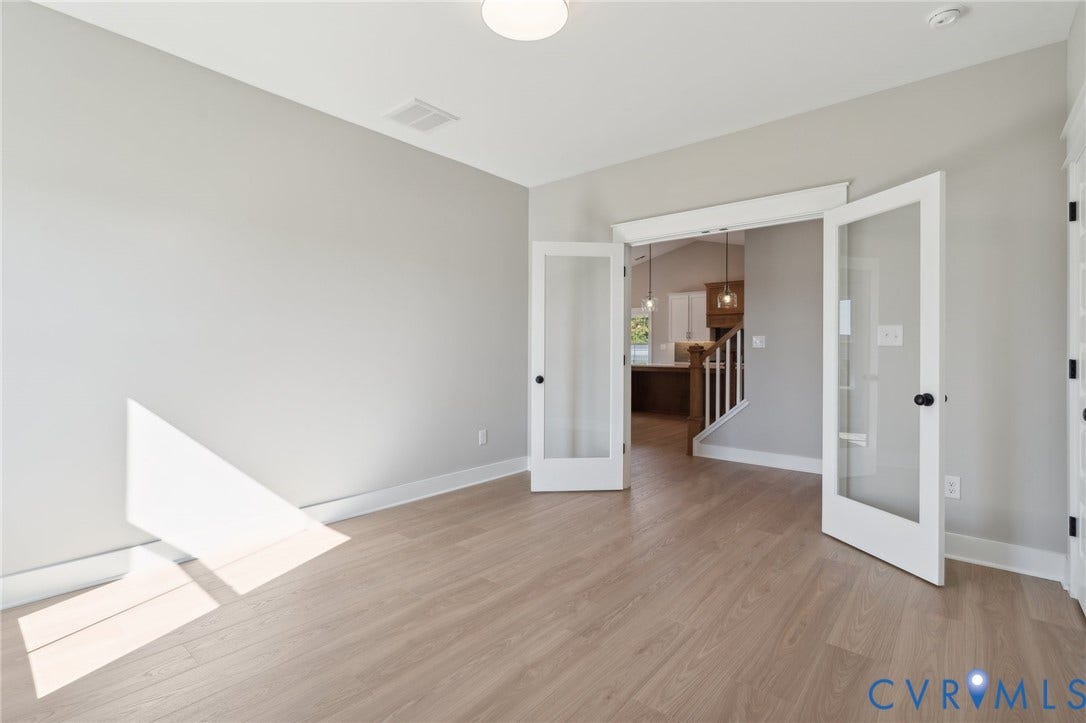 9131 Terroir Lane, Viniterra Villas, New Kent, VA 23124 Neutral-toned interior space featuring wood-finish flooring and white French doors with glass panes