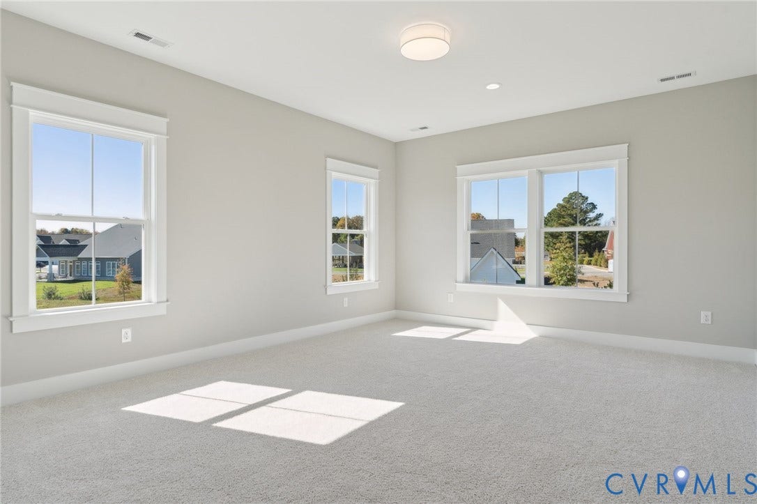 9131 Terroir Lane, Viniterra Villas, New Kent, VA 23124 Neutral-toned interior featuring wall-to-wall carpeting, multiple double-hung windows with white casing, and a modern flush-mount light fixture