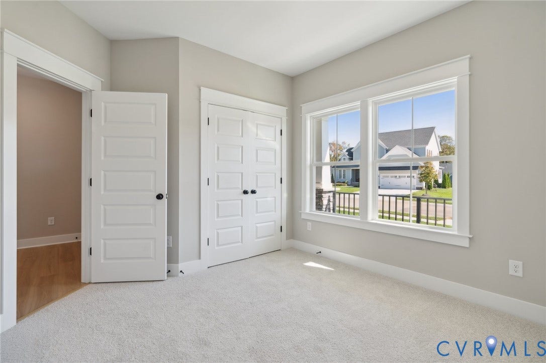 9131 Terroir Lane, Viniterra Villas, New Kent, VA 23124 Neutral-toned interior featuring wall-to-wall carpeting, multi-pane windows with detailed casing, and white four-panel interior doors with matte black hardware