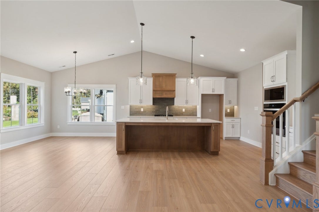 9131 Terroir Lane, Viniterra Villas, New Kent, VA 23124 Kitchen featuring a vaulted ceiling, wood-finish flooring, two-tone cabinetry with an integrated vent hood, a center island with countertop seating, and built-in wall appliances
