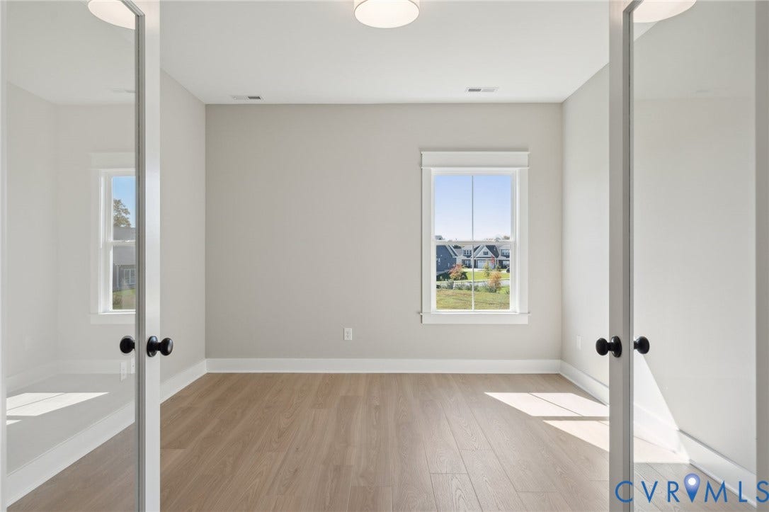 9131 Terroir Lane, Viniterra Villas, New Kent, VA 23124 Room featuring wood-finish flooring, white French doors with matte black hardware, and a window with white casing