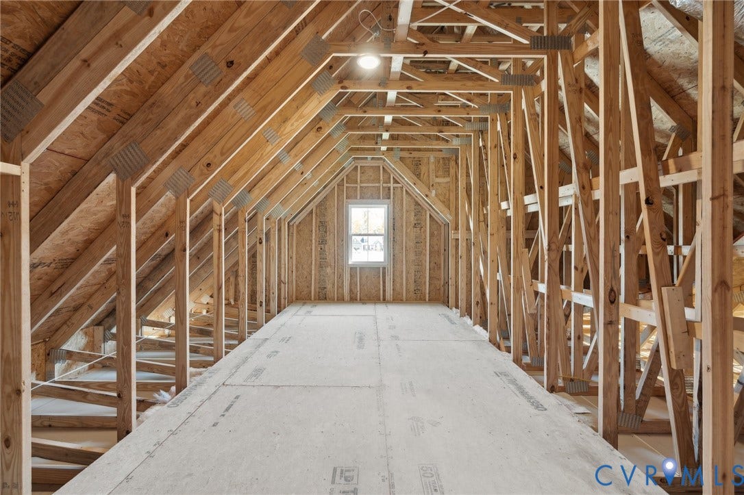 9131 Terroir Lane, Viniterra Villas, New Kent, VA 23124 Unfinished attic space featuring exposed wood framing, gable truss construction, plywood subflooring, and a singular window