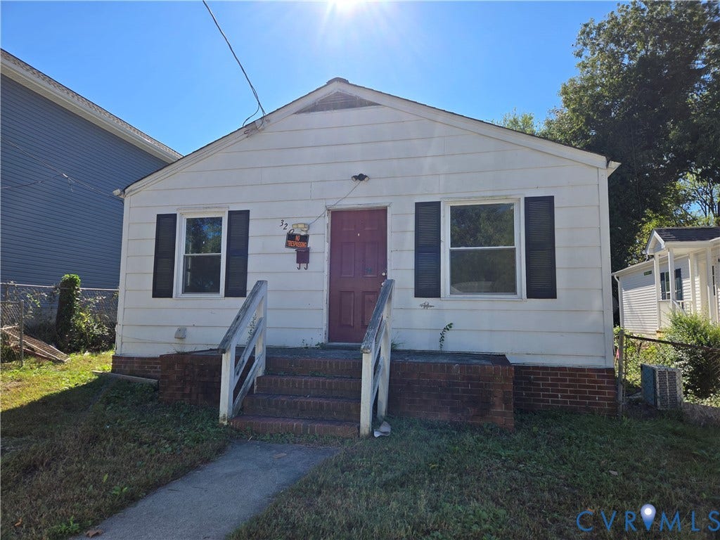 320 Shore Street, Petersburg, VA 23803 Single-story exterior featuring white horizontal siding, dark decorative shutters, brick masonry foundation, and front steps with railings