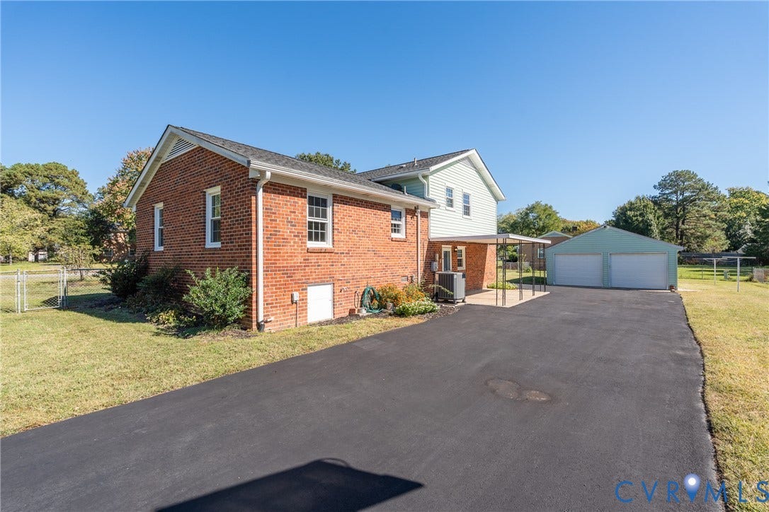 9329 Totopotomoy Trail, Ashland, VA 23005 Brick exterior, asphalt driveway, detached two-car garage, and covered patio