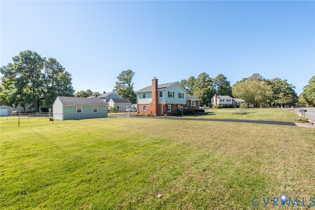 9329 Totopotomoy Trail, Ashland, VA 23005 Two-story residence with brick and siding exterior, expansive lawn, asphalt driveway, and detached storage structure