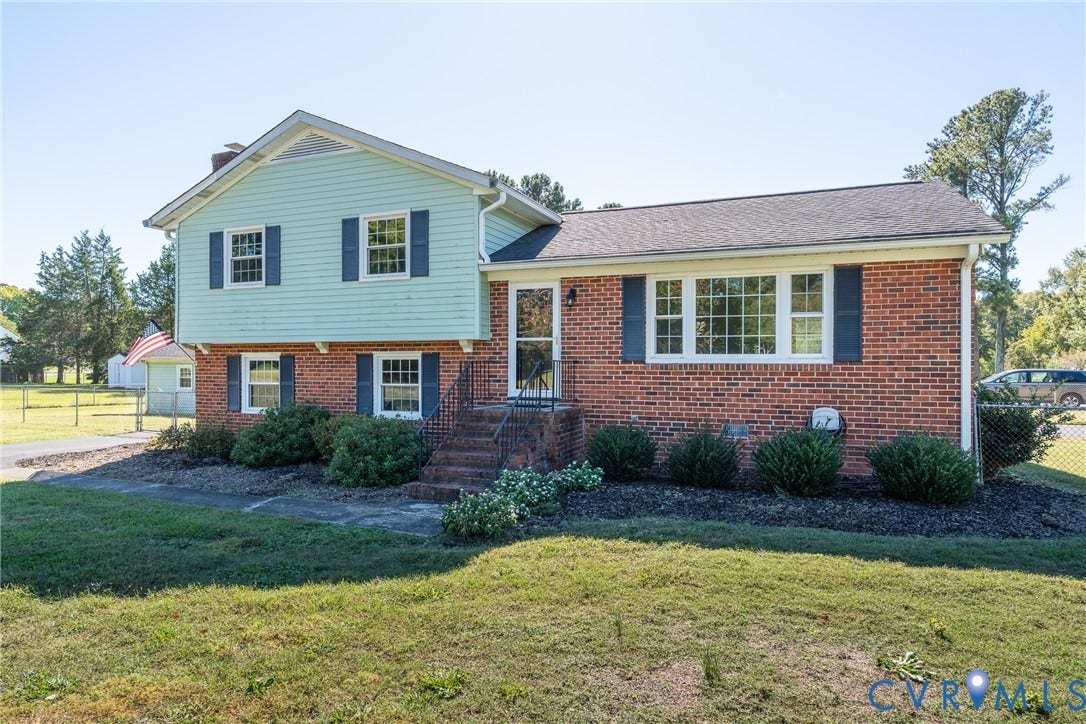 9329 Totopotomoy Trail, Ashland, VA 23005 Split-level exterior featuring a brick and horizontal siding facade, asphalt shingle roof, multi-pane windows with shutters, and a masonry front entry staircase